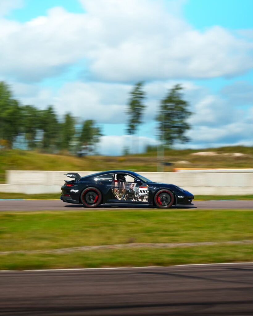 En svart Porsche 911 992 GT3 PDK kör på racerbana.